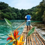 A man on raft with flowers in the water.