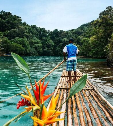 A man on raft with flowers in the water.